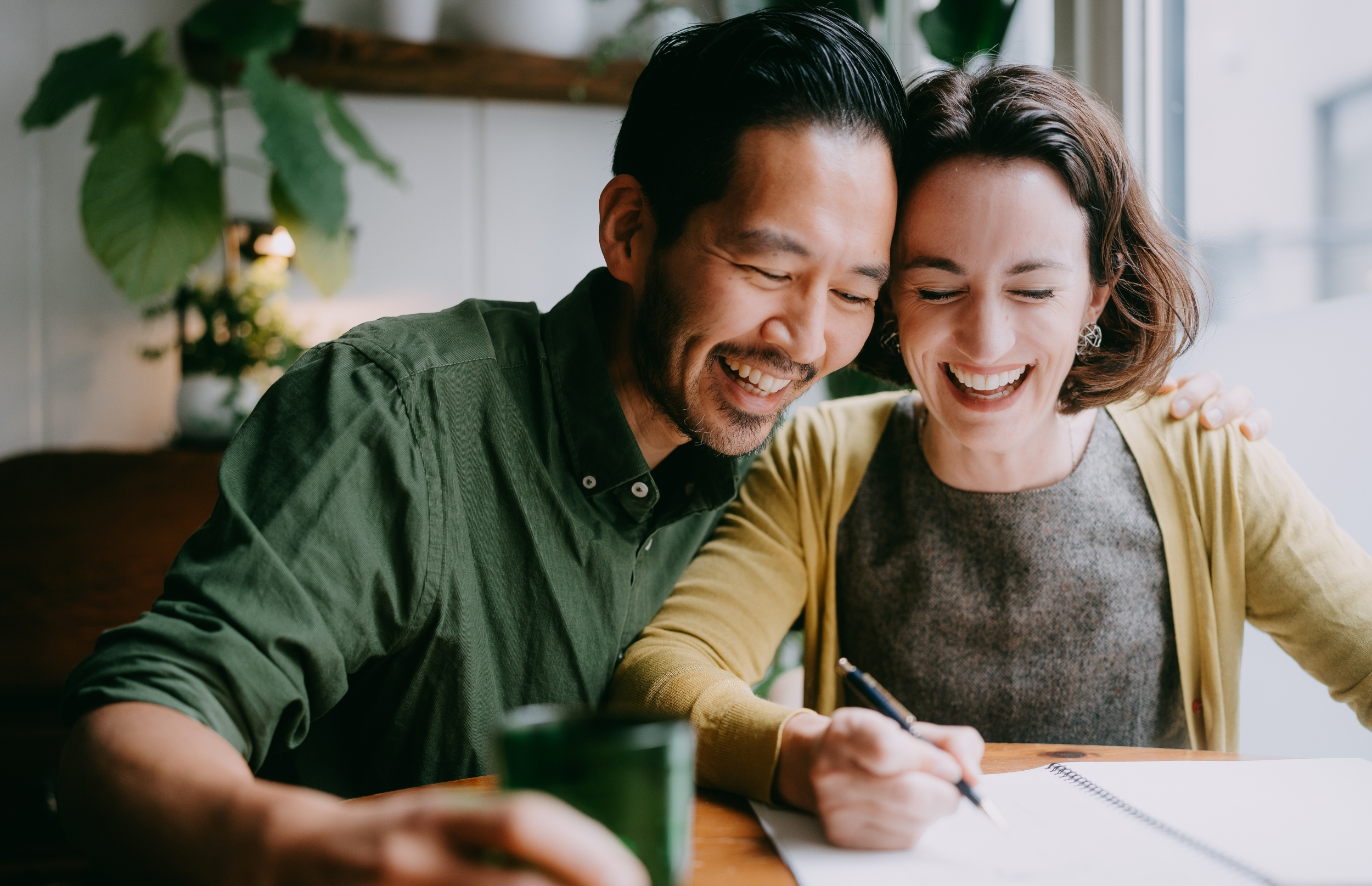 Couple shares a laugh while writing in a planner