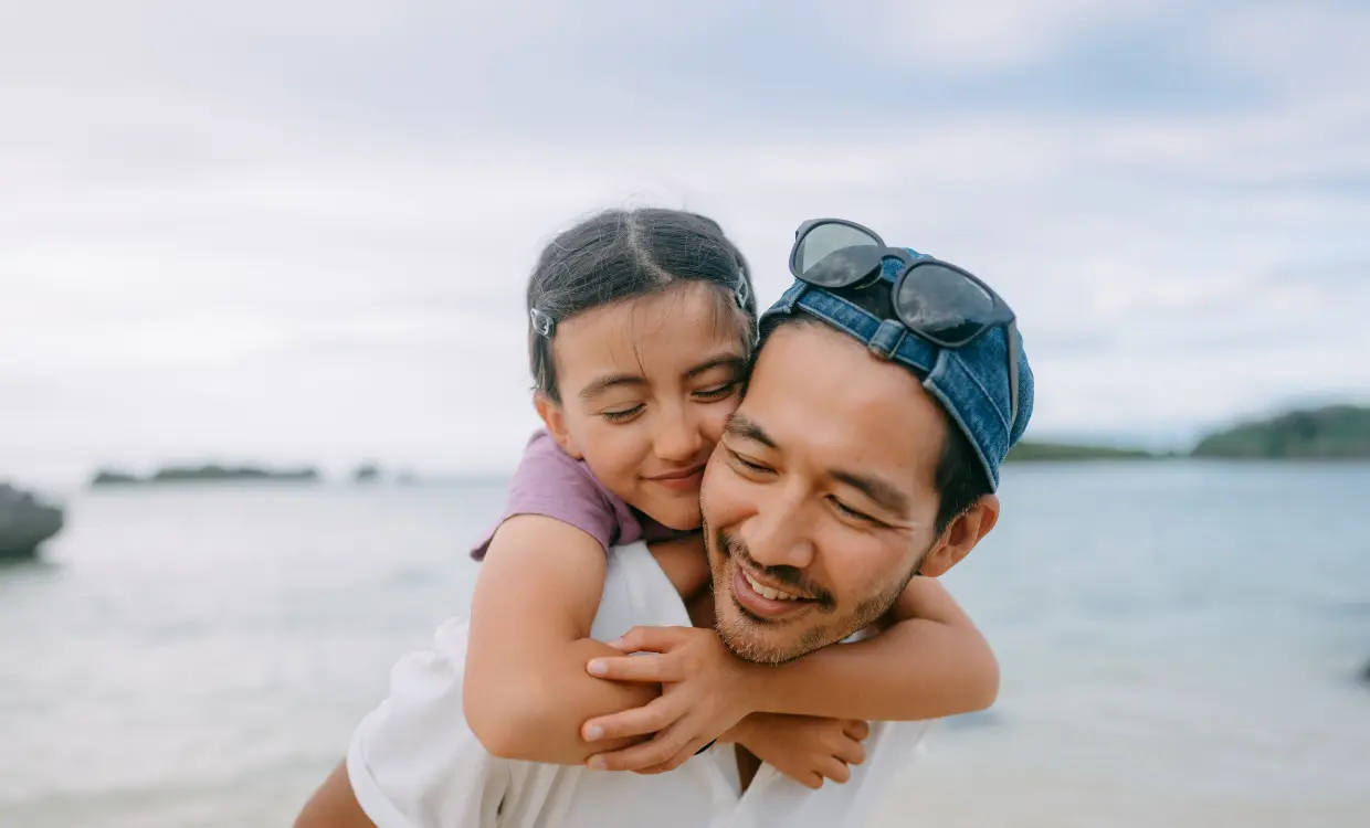 Daughter hugs her father while he gives her a piggy-back ride