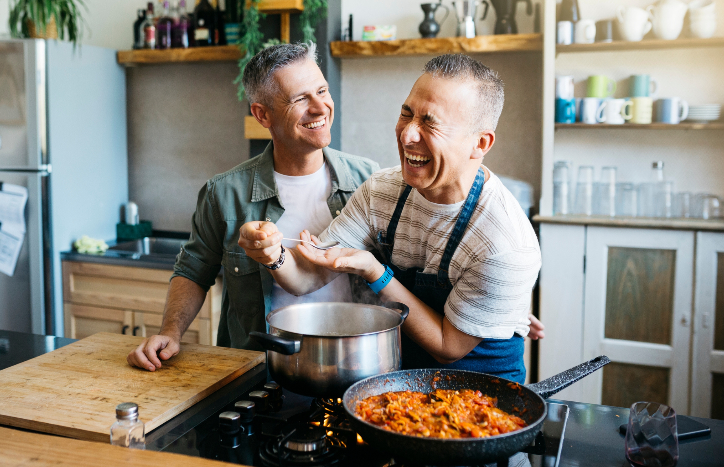 Couple laughs while taste testing the food they are cooking