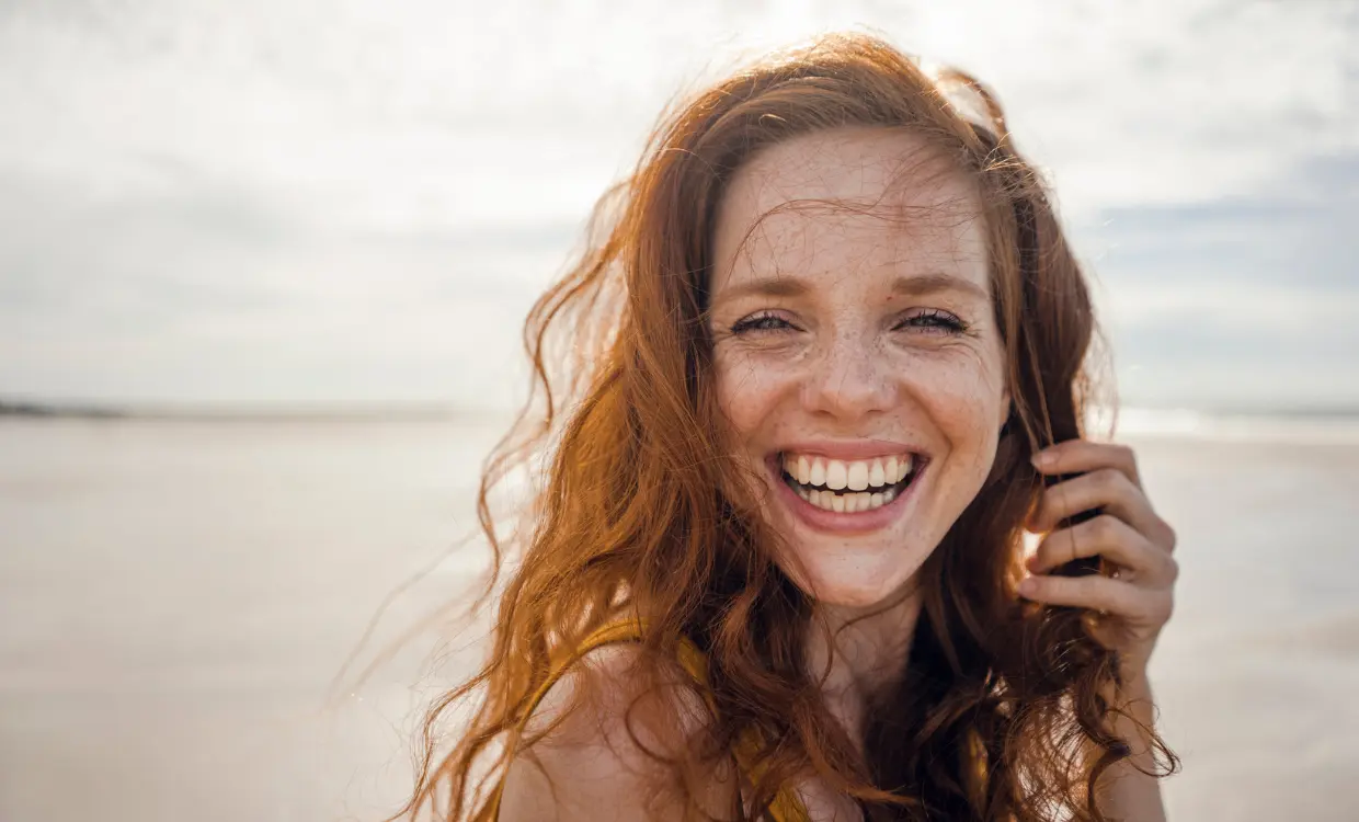 Woman smiles at camera while on the beach