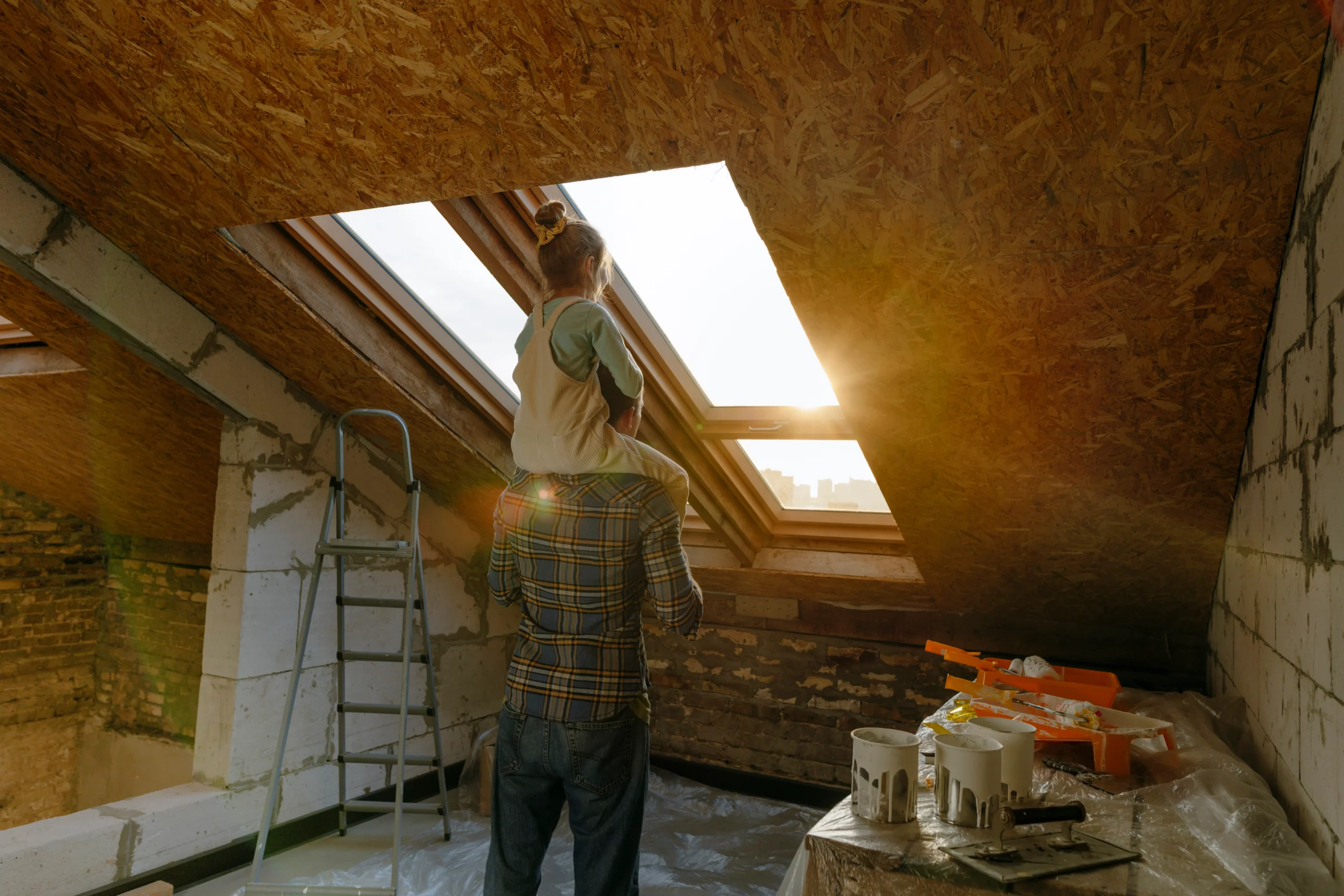 Father and daughter looking out window in attic.