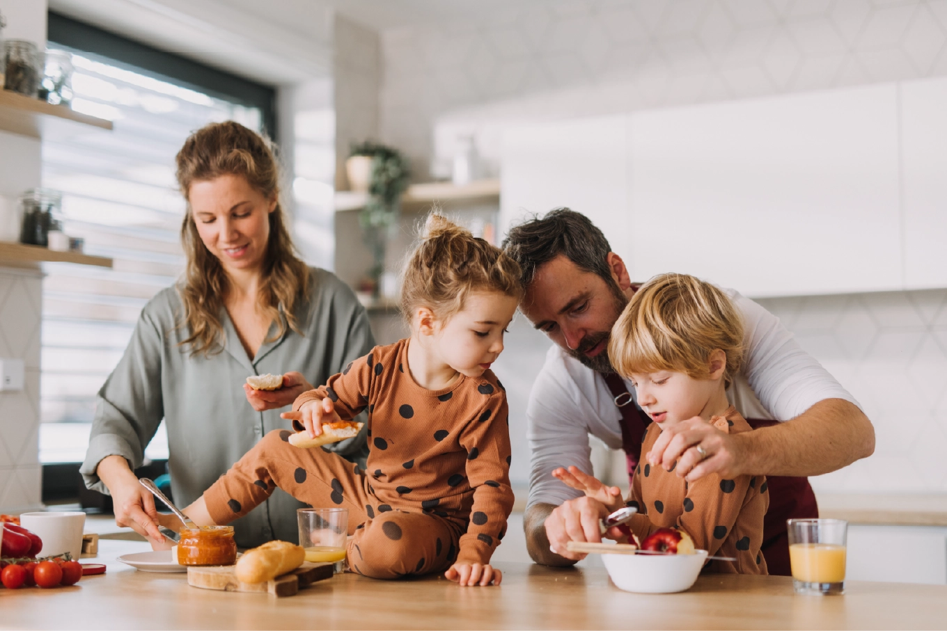 Happy family preparing breakfast together in a modern kitchen, with parents and kids enjoying a fun morning activity.