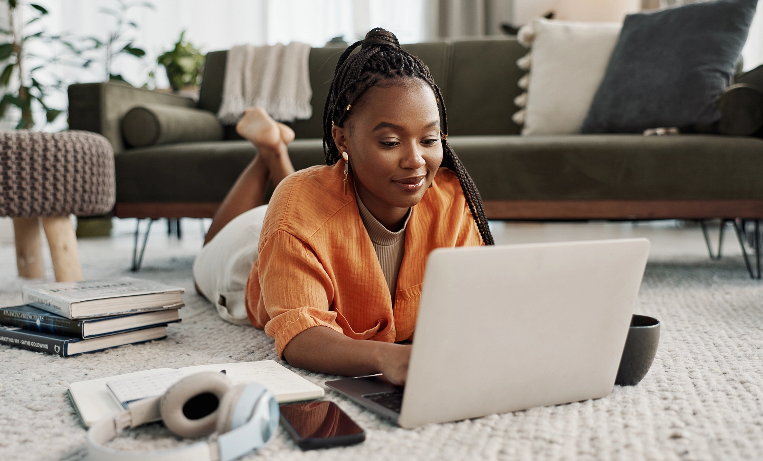 Woman grins while working on her computer on the floor