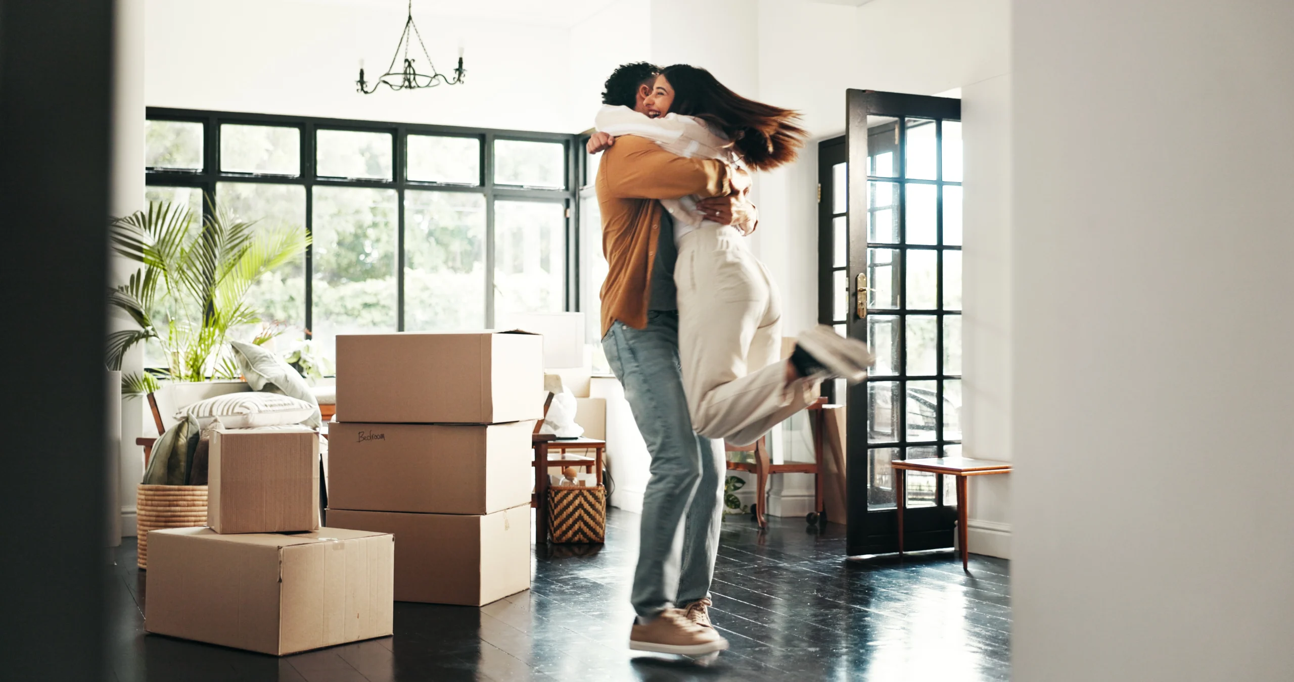 Couple rejoicing in the living room of their first home.