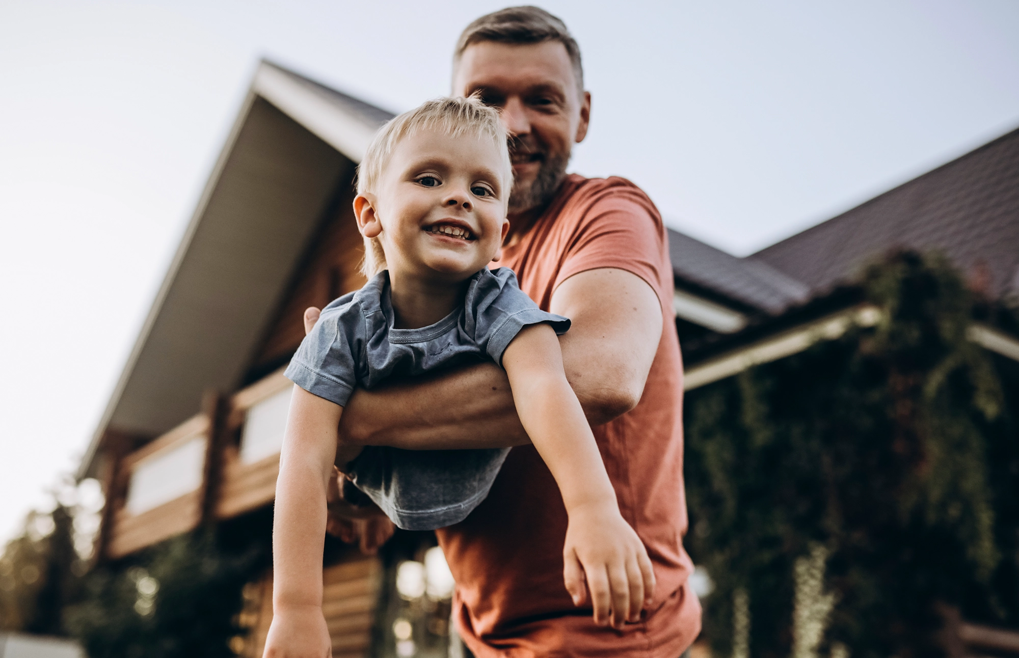 Young boy smiles at camera while his father holds him