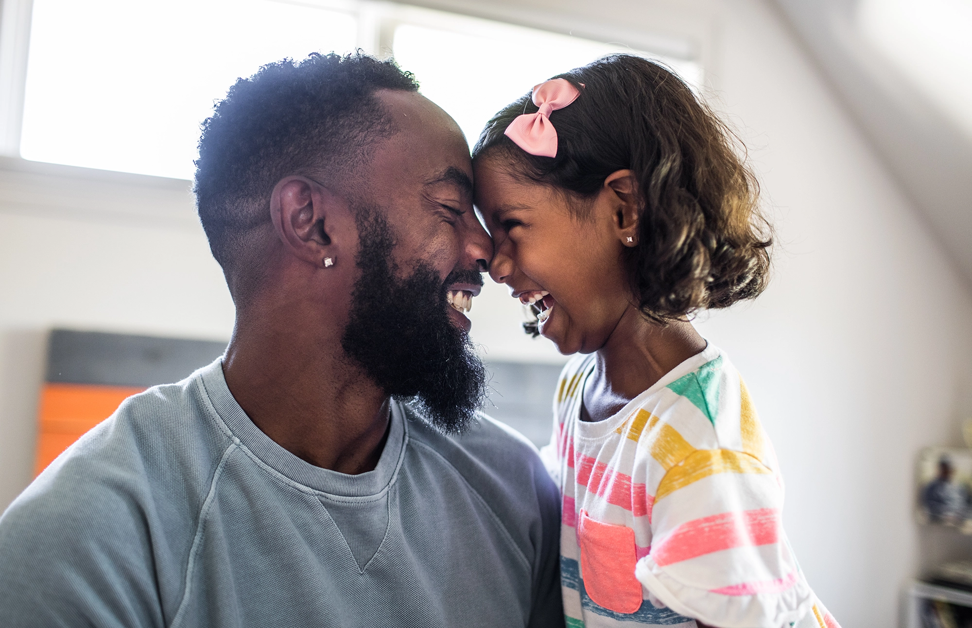 Father and daughter smile while looking at each other