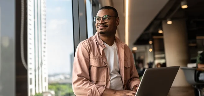 Man working on his computer while looking out the window