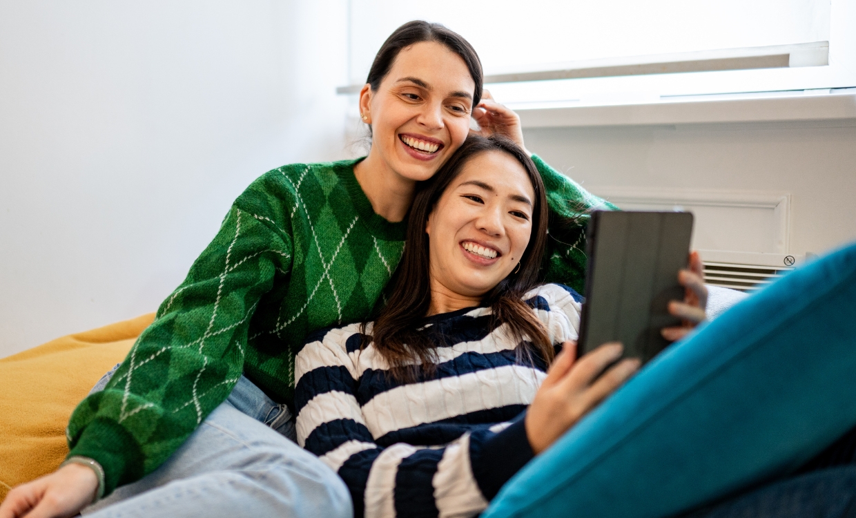 Two women looking at a tablet while sitting on the couch