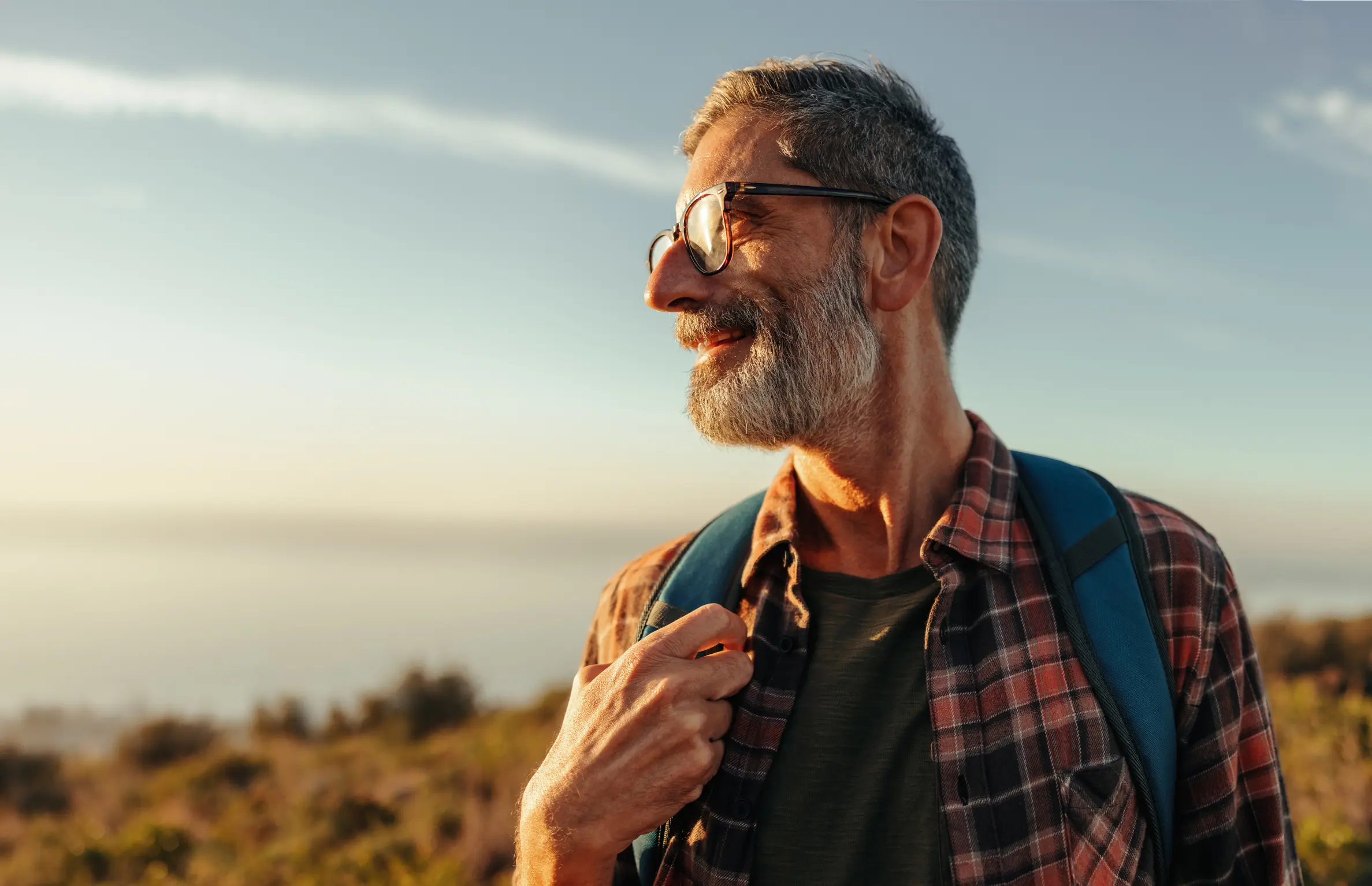 Man with glasses and beard hiking with a backpack.