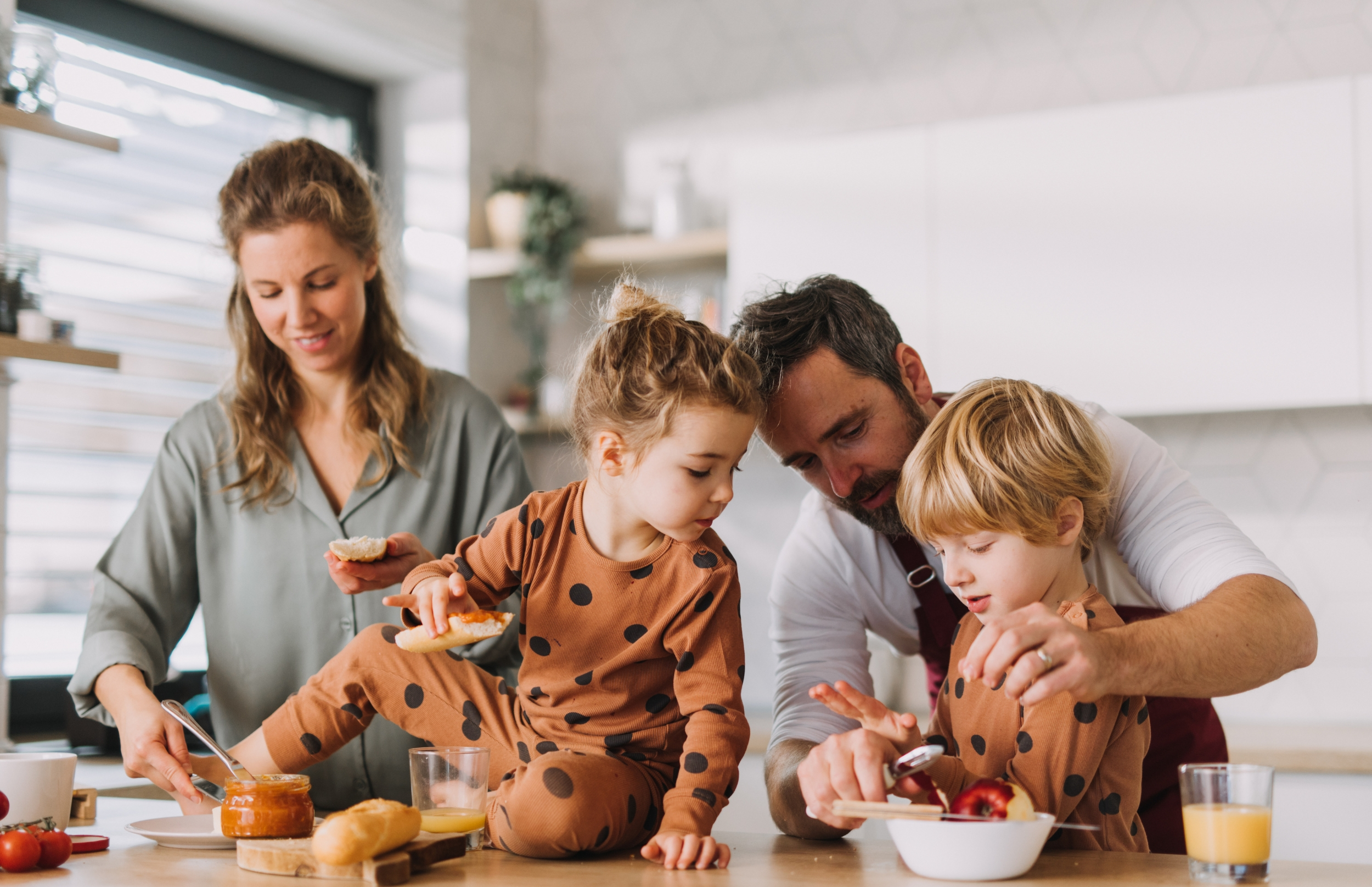 Family of four in the kitchen making lunch