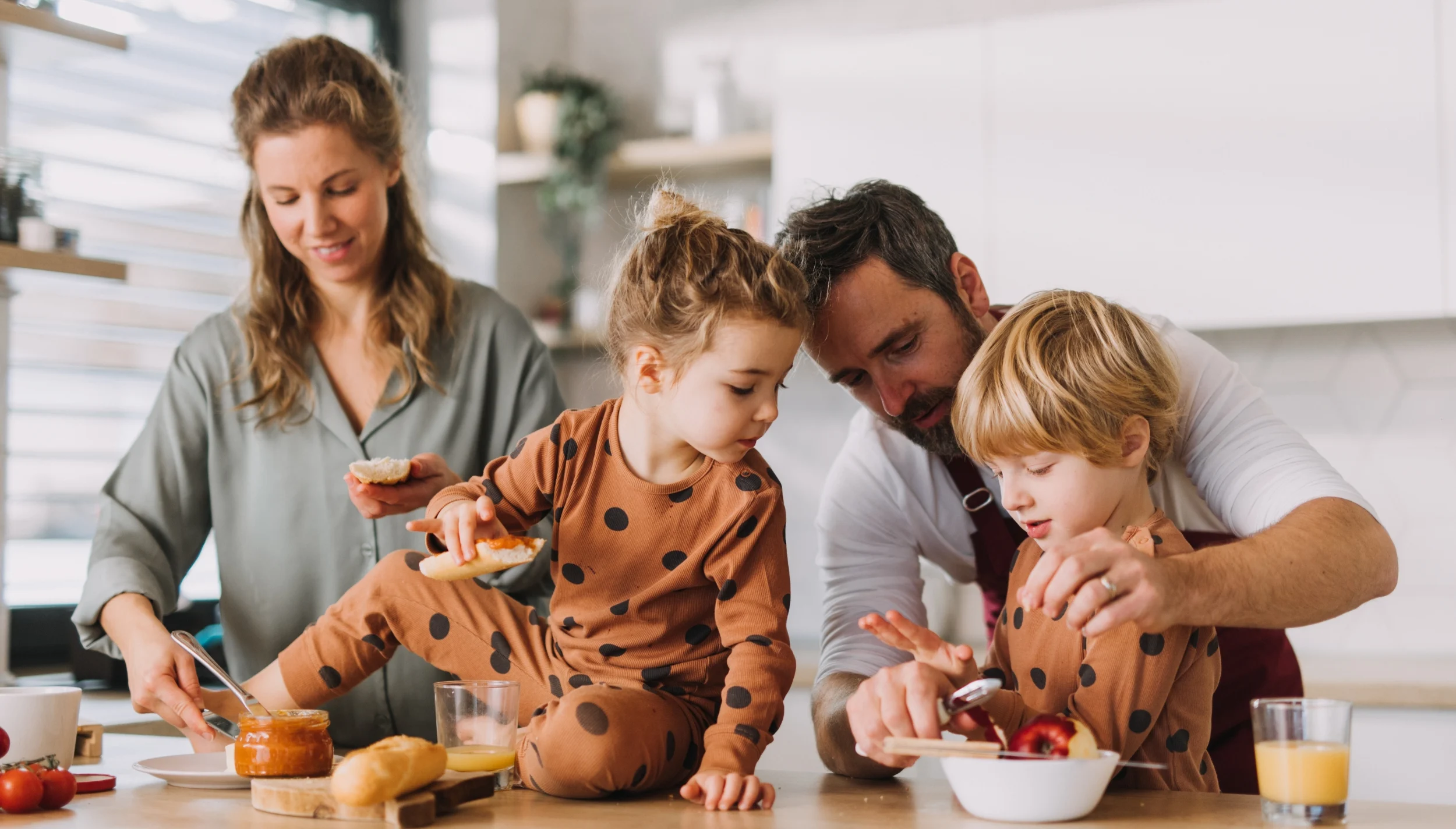 Family of four in the kitchen making lunch