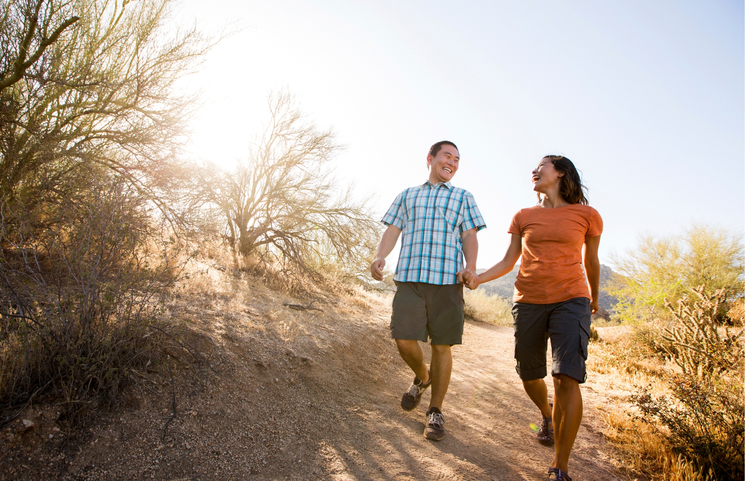 Middle-aged couple smile at each other while on a trail walk